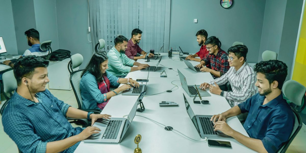 Group of professionals collaborating in a modern office setting on laptops and digital devices.