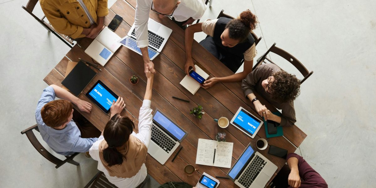 Top view of a diverse team collaborating in an office setting with laptops and tablets, promoting cooperation.